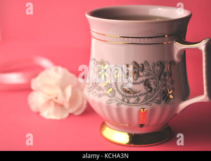 Fond rose avec rose tasse à café en porcelaine, les œillets et les copier dans l'espace. Banque D'Images