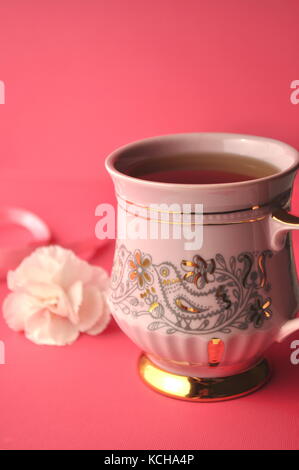 Fond rose avec rose tasse à café en porcelaine, les œillets et les copier dans l'espace. Banque D'Images