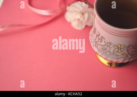 Fond rose avec rose tasse à café en porcelaine, les œillets et les copier dans l'espace. Banque D'Images