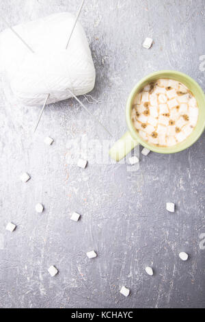 Tricot blanc ball et aiguilles en deux tasse de café avec de la guimauve sur fond gris. vue d'en haut. copie espace fil à tricoter. Banque D'Images