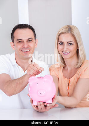 Portrait of happy couple holding piggybank ensemble Banque D'Images