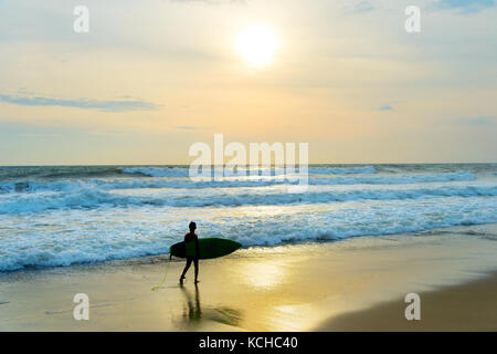 Silhouette d'un garçon de la surfer marche sur la plage. L'île de Bali, Indonésie Banque D'Images