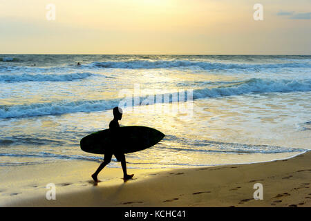 Silhouette d'un garçon de la surfer marche sur la plage. L'île de Bali, Indonésie Banque D'Images