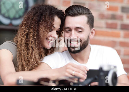 Heureux couple aimant en utilisant un smartphone assis en terrasse Banque D'Images