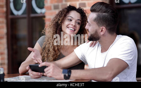 Heureux couple aimant en utilisant un smartphone assis en terrasse Banque D'Images