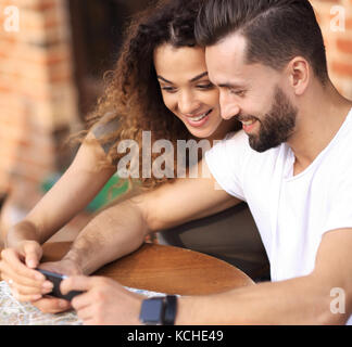 Heureux couple aimant en utilisant un smartphone assis en terrasse Banque D'Images