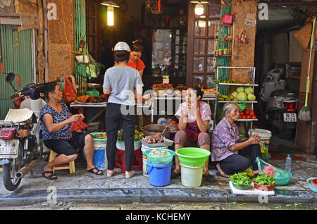 Une famille se trouve à l'extérieur d'une boutique dans le centre de Hanoi, Vietnam Banque D'Images