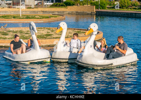 Les familles profitent de l'été sur des cygnes sur le lac en bateau dans la ville balnéaire de Hastings Banque D'Images