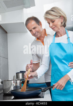 Homme recherche femme à la cuisson des aliments dans la cuisine Banque D'Images