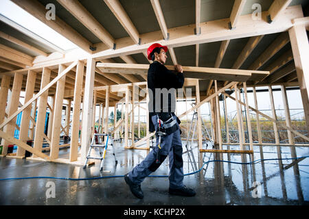 Photo de profil jeune menuisier transportant du bois at construction site Banque D'Images