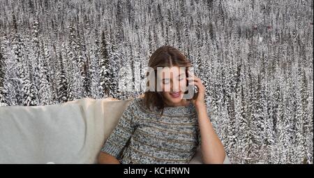 Digital composite of Woman avec cavalier sur téléphone sur table en face de la forêt de la neige Banque D'Images