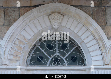 Une fenêtre supérieure semi-circulaire, avec une grille en fer stylisée à l'entrée d'une maison qui appartenait à des Palestiniens qui ont fui ou ont été expulsés pendant la guerre d'indépendance d'Israël de 1948 située sur la rue Qeen Helena ou Heleni Hamalka à l'ouest de Jérusalem Banque D'Images