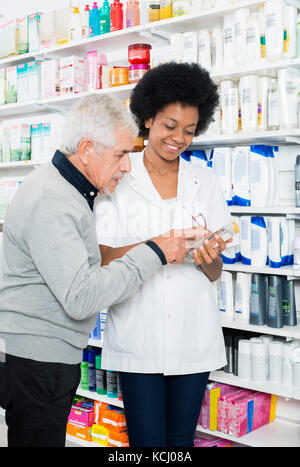 Pharmacien montrant l'information sur un produit à la clientèle senior Banque D'Images