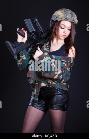 Femme de l'uniforme militaire avec un fusil d'assaut sur fond noir Banque D'Images