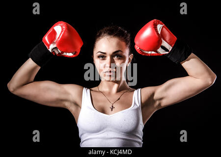 Belle jeune femme d'une gants de boxe rouge sur fond noir Banque D'Images