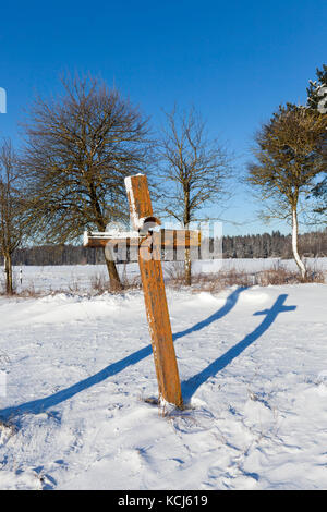 Vieux bois croix de fléchissement dans le domaine et couverte de neige en hiver. sur la surface de la croix, la peinture qu'il a été peint Banque D'Images