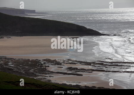 Dunraven bay près du village de Southerndown avec la marée bien dehors et un groupe de personnes se tenait sur la mer et les promeneurs de chiens environ. Banque D'Images