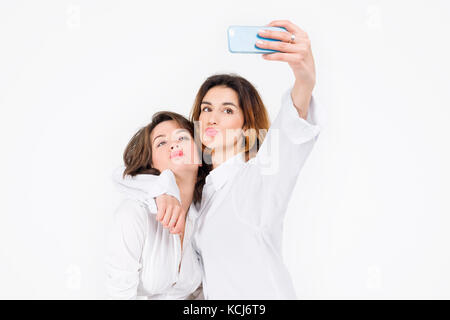 Deux femmes se posant dans le Light Studio selfies. girls best friends making grimaces sur appareil photo, montrant la langue et rire ensemble. Banque D'Images