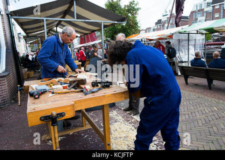 Leiden, Pays-Bas 3 octobre 2017. La foire locale du marché d'amusement avec des sculpteurs sur bois de travailler à un banc de travail du bois de rédaction. Banque D'Images