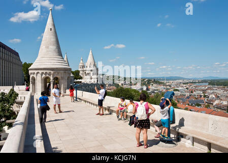 Touristes sur les murs du Bastion des pêcheurs à Budapest regardant la vue et prenant des photos lors d'une journée ensoleillée avec le ciel bleu. Banque D'Images