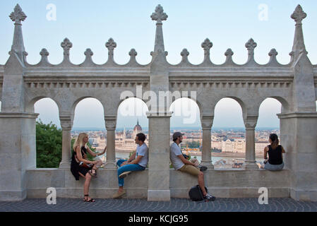 Quatre 4 personnes, deux couples touristes sur les murs du Bastion des pêcheurs en admirant la vue de Budapest avec le ciel bleu, tout comme le soleil s'est couché. Banque D'Images