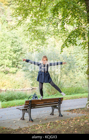 Jeune femme sautant par-dessus le banc en bois dans un parc public, luxembourg Banque D'Images