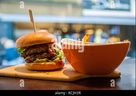 Délicieux burger et frites sur la planche à découper en bois Banque D'Images