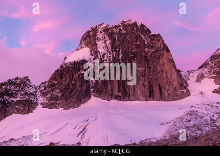 Les nuages roses éveillent Snowpatch Spire au lever du soleil dans le parc provincial de Bugaboo, Purcell, British Columbia, Canada. Banque D'Images