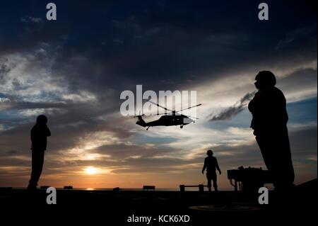 Un hélicoptère MH-60S Seahawk de l'US Navy atterrit sur le pont d'envol à bord du navire de combat littoral USS Coronado de classe Independence de l'US Navy au coucher du soleil le 5 août 2017 dans la mer de Chine méridionale. (Photo de MCS3 Deven Leigh Ellis via Planetpix) Banque D'Images