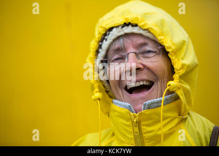 Un rire heureux, Senior citizen habillés en jaune elle bénéficie d'office de la tempête alors qu'à bord du MV Uchuck III, Friendly Cove, l'île de Vancouver, Colombie-Britannique, Canada. Banque D'Images