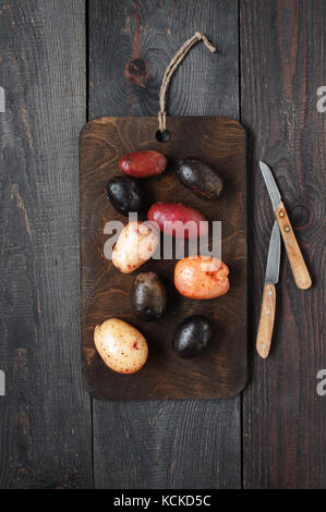 Colorés frais pommes de terre sur la planche de bois et des couteaux de cuisine Banque D'Images