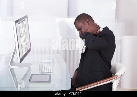 Young businessman in office à 24 souffrant de douleur au cou Banque D'Images