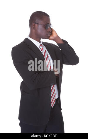 Portrait d'un jeune homme africain en litige portant des lunettes de soleil sur fond blanc Banque D'Images