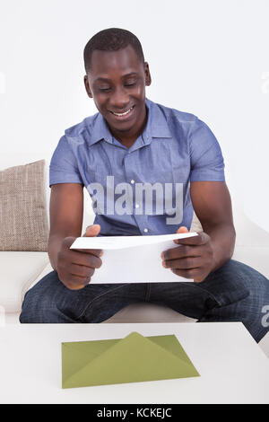 Les jeunes heureux homme africain la lecture à la maison de l'enveloppe Banque D'Images
