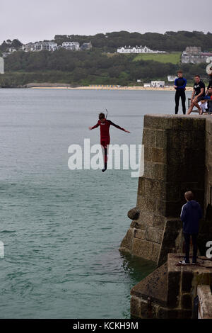 Un jeune homme sautant du quai dans le port de St Ives, Cornwall Banque D'Images