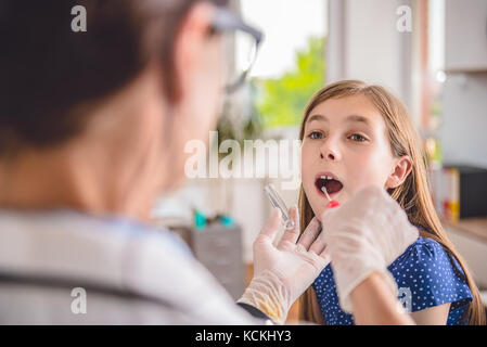 À l'aide d'un pédiatre femelle coton-tige pour prélever un échantillon de la gorge d'un patient Banque D'Images