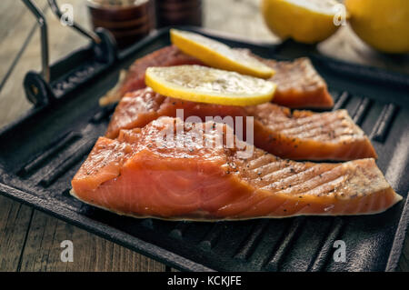 Big Pink tranche de saumon aux fines herbes et citron repose sur un poêle noir. Banque D'Images