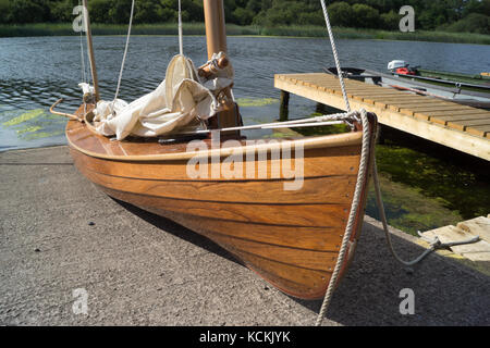 L'homme en bois de deux canots à voile sur cale avec deux (2) mâts voiles ferlées, mais est prêt à se lancer dans la rivière derrière Banque D'Images