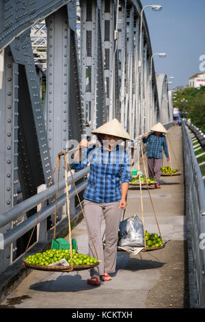 Les vendeurs de rue marcher avec leurs produits frais du marché de Dong Ba à Truong Tien pont (Cầu Trường Tiền) Banque D'Images