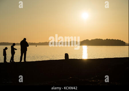 Silhouette d'un homme et ses deux enfants avec des cannes à pêche, dans le golfe du Morbihan, dans la soirée, à Vannes (Bretagne, nord-ouest de la France). Le Banque D'Images