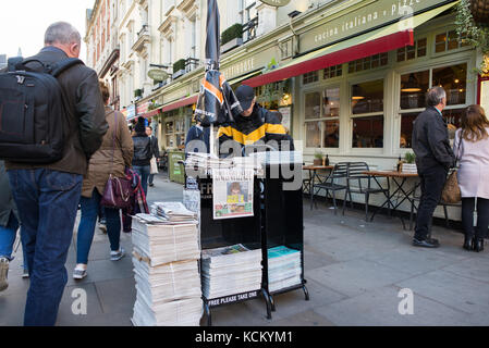 Vendeur de journaux distribuant gratuitement des copies de l'Evening Standard à un stand Street, London, England, UK Banque D'Images