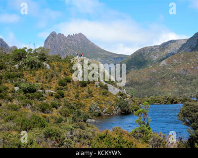 Quatre randonneurs dans un affleurement rocheux au-dessus du lac Dove avec Cradle Mountain derrière. Parc national Cradle Mountain-Lake St clair, Tasmanie, Australie Banque D'Images