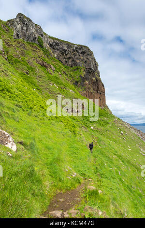 Une marchette sur la piste sous les falaises du côté ouest du plateau Beinn Bhuidhe, île d'Eigg, Écosse, Royaume-Uni Banque D'Images