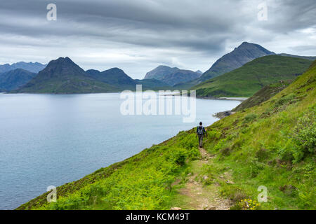 Un marcheur sur le sentier côtier d'Elgol à Camasunary, aux côtés du Loch Scavaig, de l'île de Skye, en Écosse, au Royaume-Uni. Banque D'Images