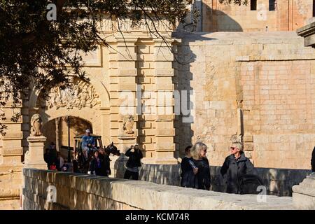 Cheval et chariot et touristes traversant la porte de la ville passerelle, Mdina, Malte, l'Europe. Banque D'Images