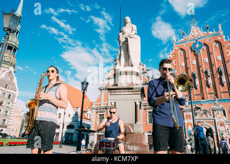 Riga, Lettonie - 1 juillet 2016 : street music trio groupe de trois jeunes musiciens gars jouant les instruments pour le don sur la place de l'hôtel de ville, célèbre Banque D'Images