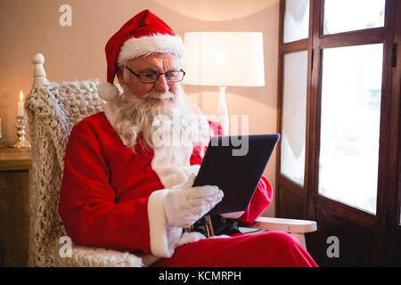 Santa Claus using digital tablet in living room pendant la période de Noël Banque D'Images