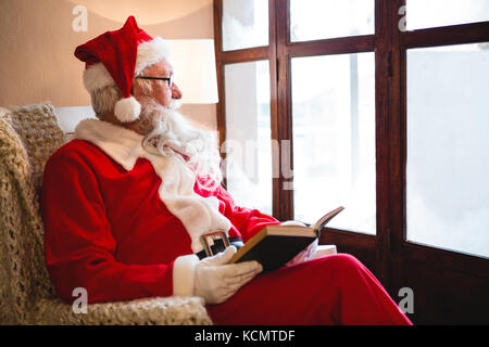 Père Noël roman lecture réfléchie dans la salle de séjour pendant la période de Noël Banque D'Images