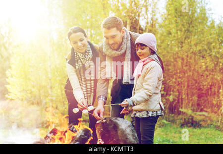 Famille heureuse le rôtissage de la guimauve sur feu de camp Banque D'Images