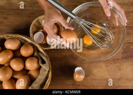 La mi-section de l'homme à casser les œufs dans un bol Banque D'Images